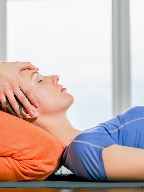Thai massage element Close up portrait young beautiful girl making face head massage. Model lying on the knees of a masseuse in a yoga studio. Treatment, rest, relaxation, health skin care, spa
